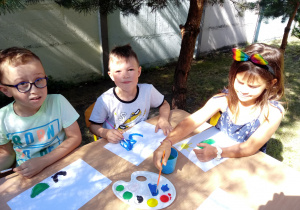 Dzieci malują farbami w ogrodzie